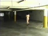 High heeled brunette walks through parking area nude.